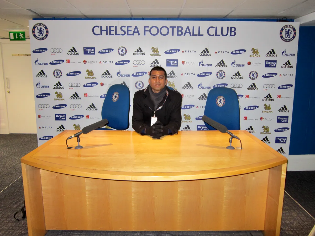 Besökare som sitter bakom tränarens skrivbord i presskonferensrummet under en Chelsea stadiontur